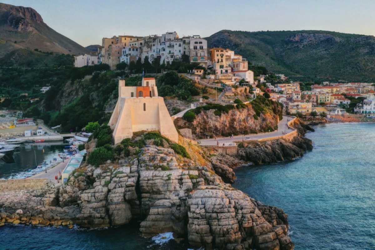 Navetta Cotral o autobus davanti alla stazione Fondi-Sperlonga, con viaggiatori e indicazioni per Sperlonga. Atmosfera dinamica, viaggio verso la spiaggia.