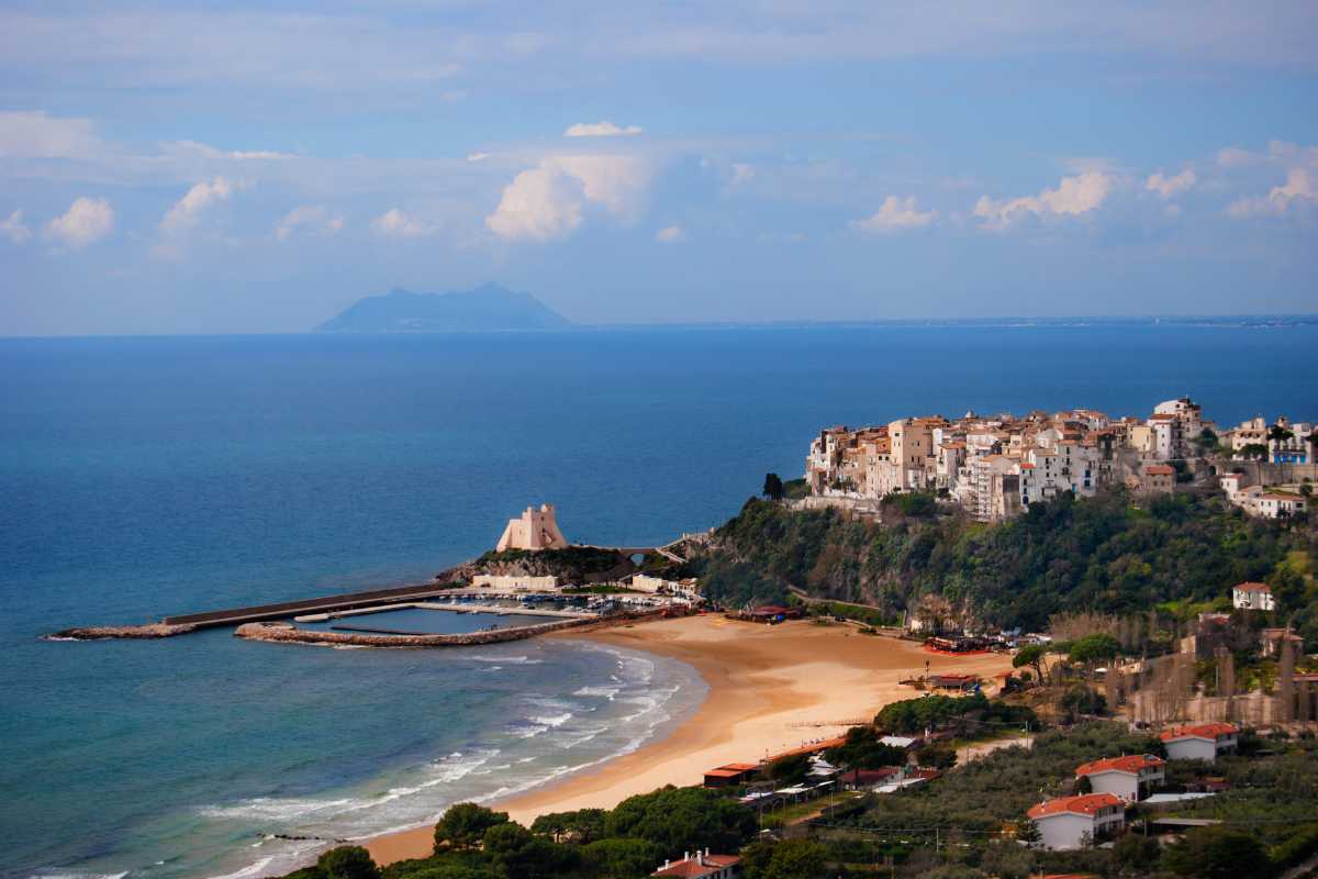 Scatto ravvicinato di un vicolo lastricato nel centro storico di Sperlonga, decorato con vasi di fiori colorati e luci serali